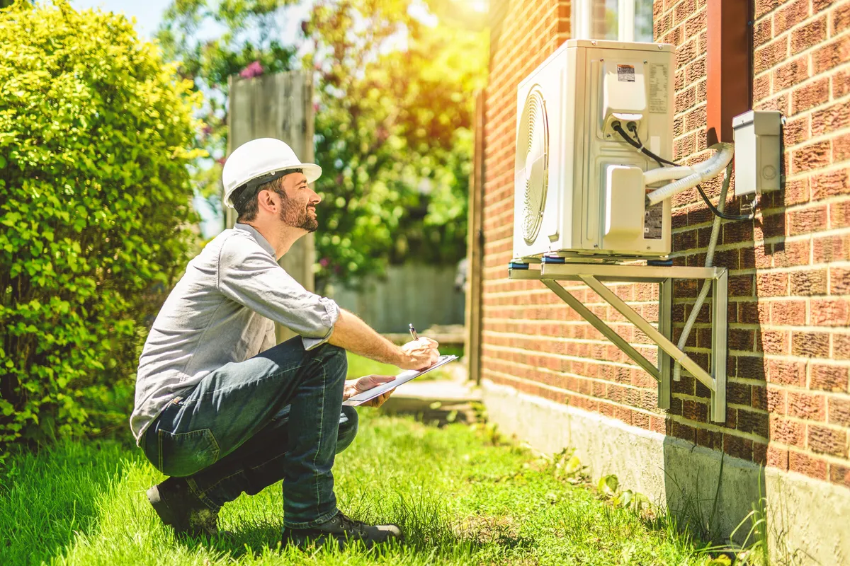 Technician inspecting an outdoor heat pump unit — illustrative stock photo, not an actual St. George job site