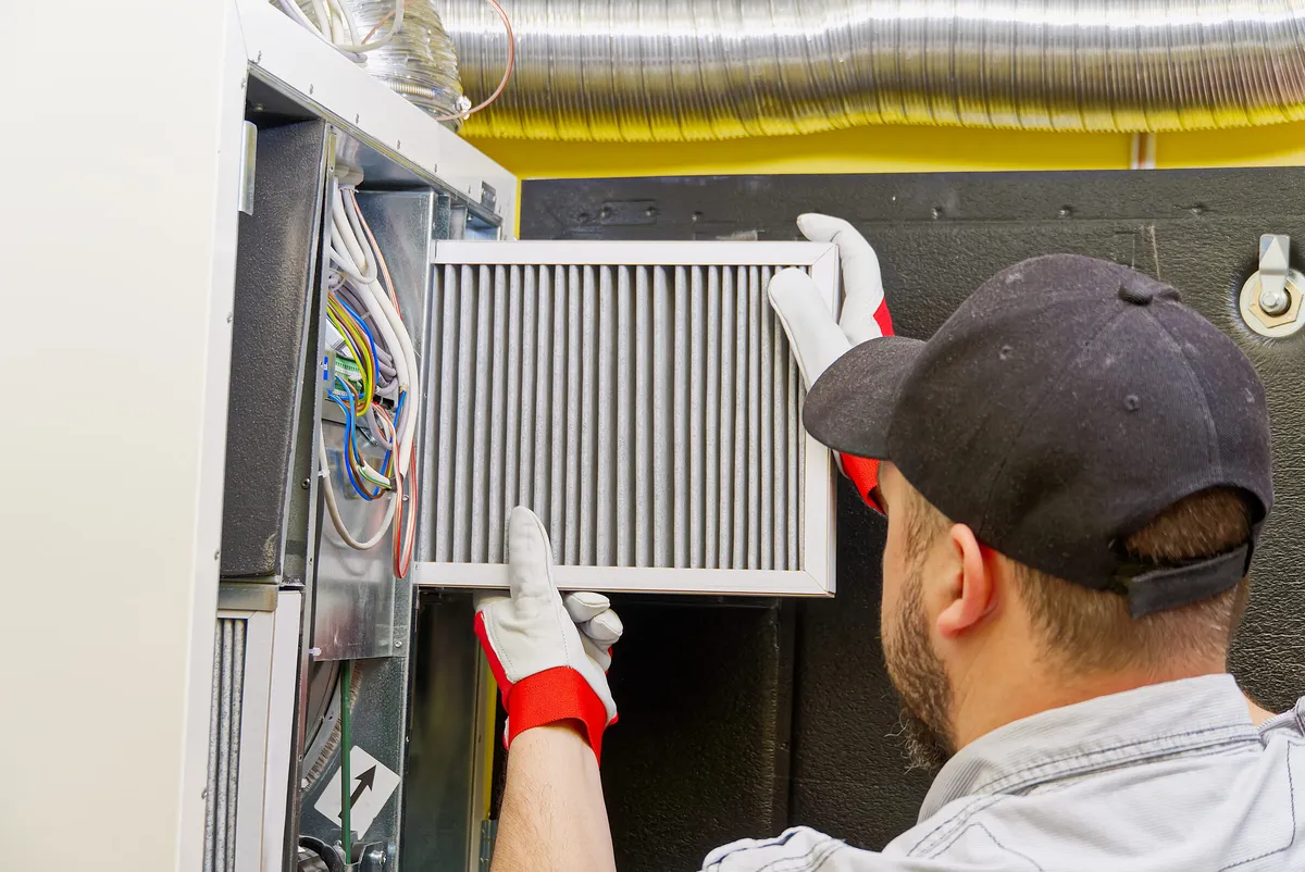HVAC technician changing a whole-house air filter — illustrative stock photo, not an actual St. George job site