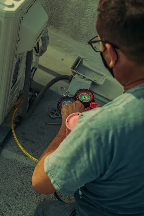 HVAC technician using pressure gauges to diagnose a residential air conditioning system — illustrative stock photo, not an actual St. George job site